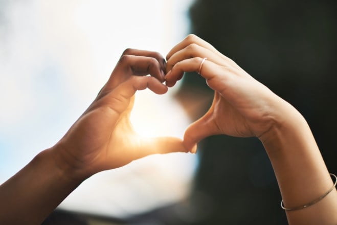Cropped shot of a couple making a heart gesture with their hands outdoors